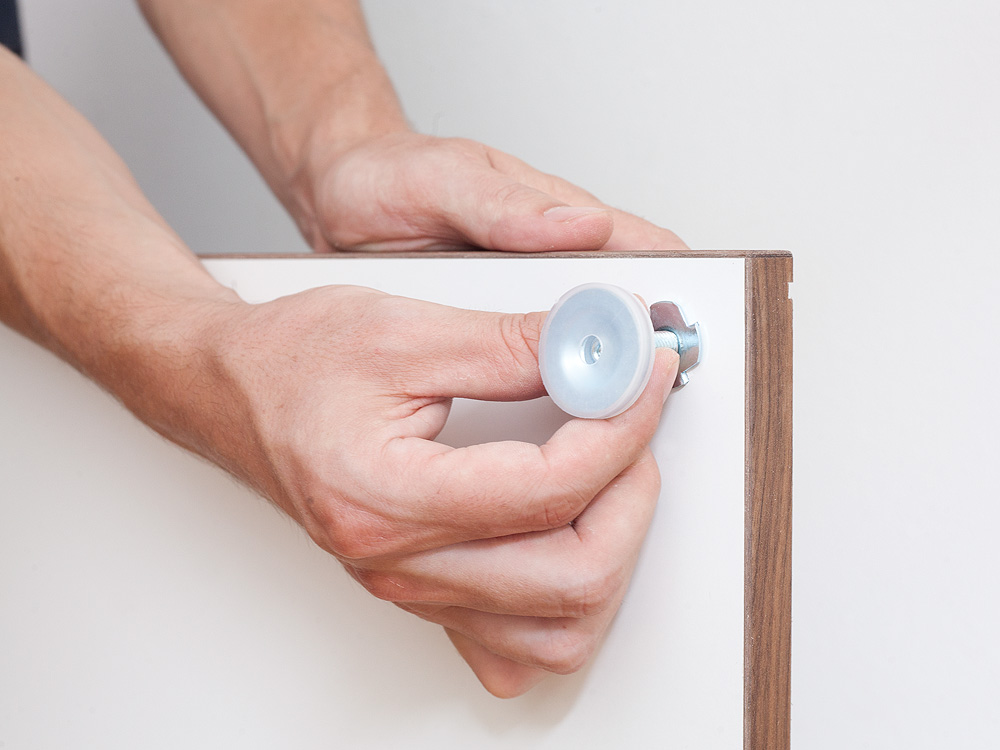 Ein Stellfuß wird in den Sockel geschraubt