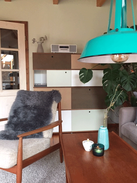 Tisch mit Vase neben Sessel im Hintergrung Schrank